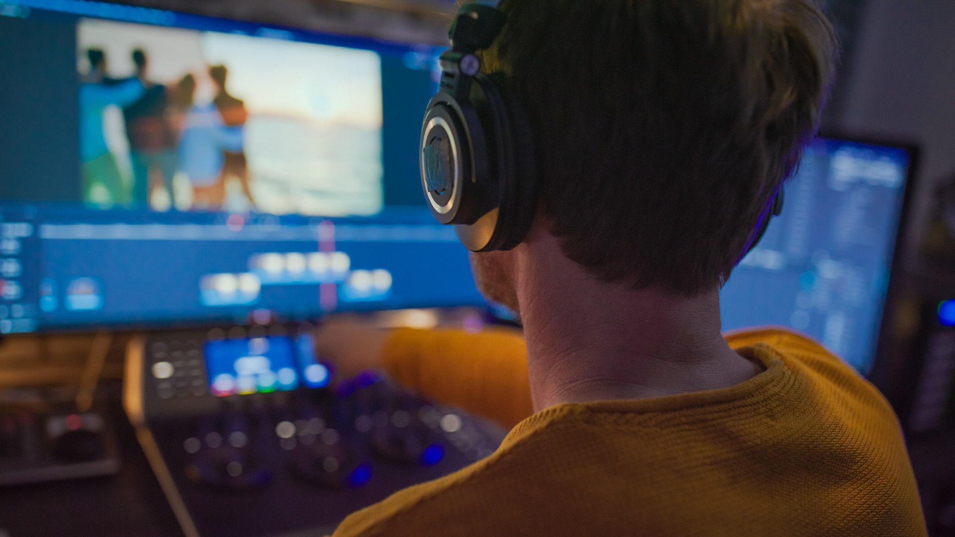 Male editor working with footage on computer screens at desk